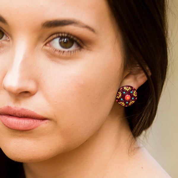 Close-up of a model wearing hand-painted stud earrings handmade from polymer clay